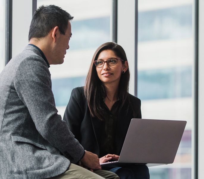 Man of Asian descent discussing business with a colleague in Charter office