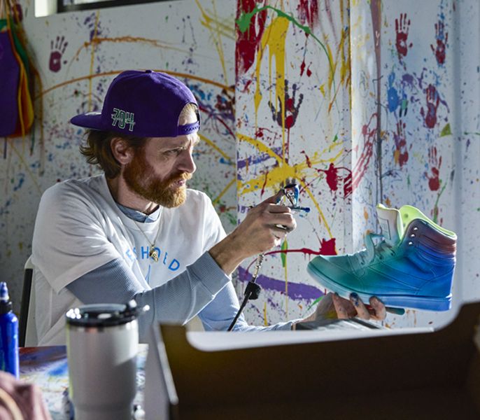 Small business owner custom painting a sneaker in his shop 