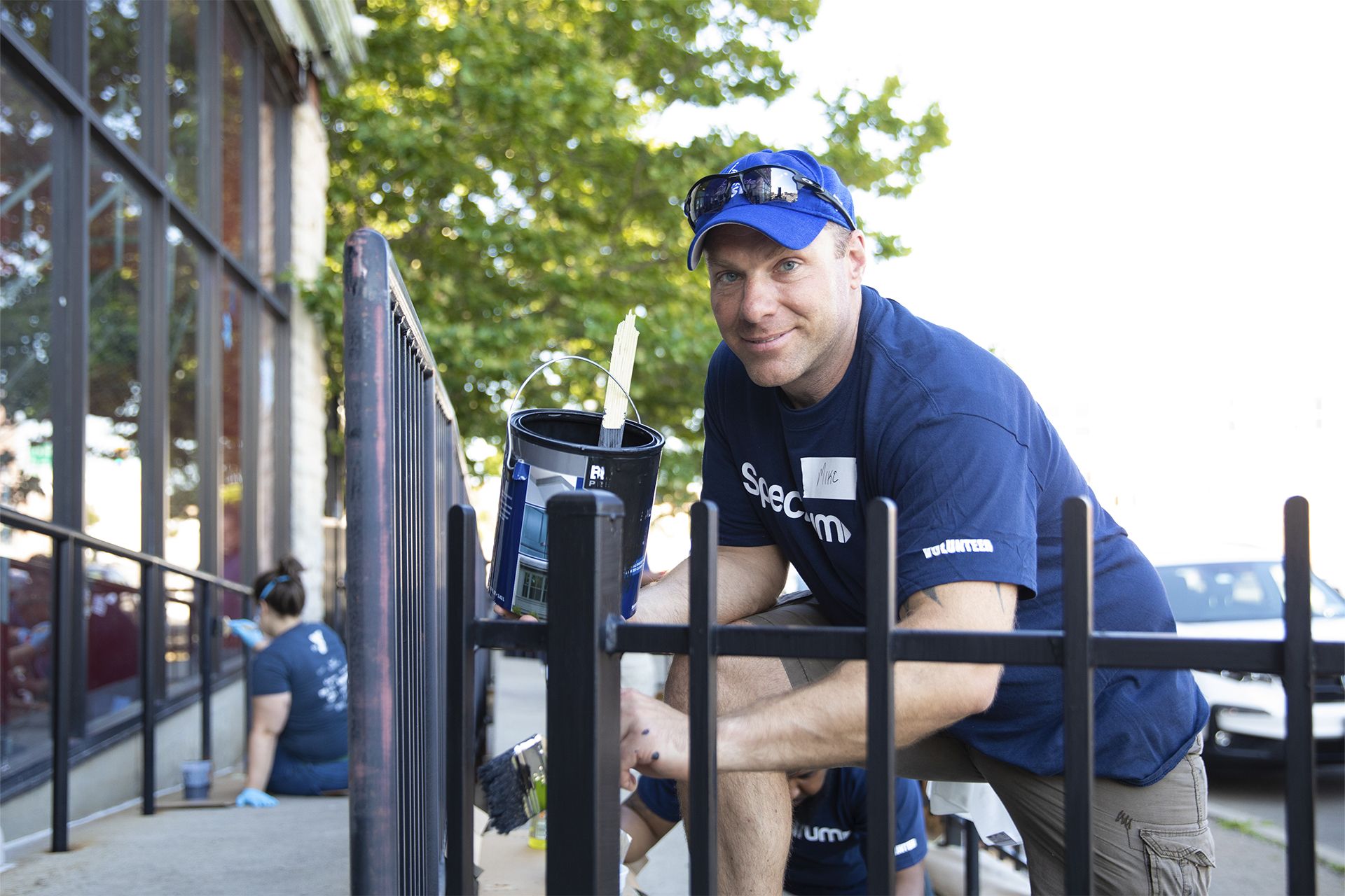 A Spectrum volunteer painting a fence at a community center