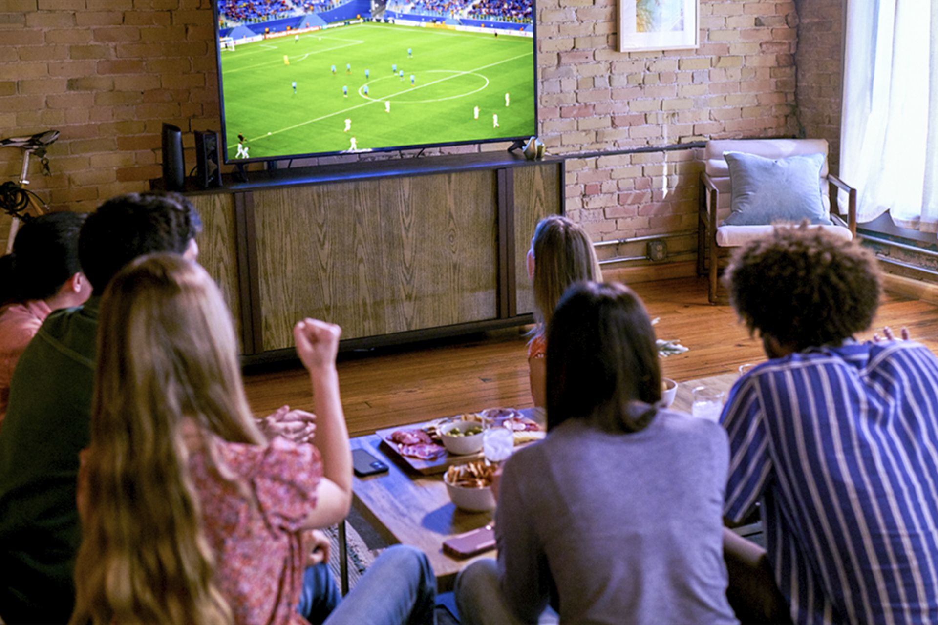 Family watching TV on their couch, viewed from behind